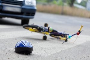 A small bike and a helmet lying on the road.