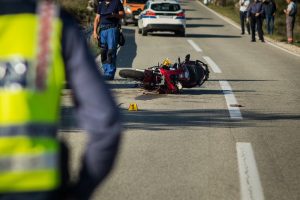 Car and a red sport motorcycle crash scene on an open road in afternoon.