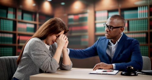 attorney placing reassuring hand on distressed client's shoulder in law office